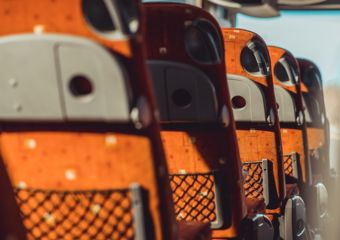 interior of a charter bus showing seats with seat-back trays and storage compartments