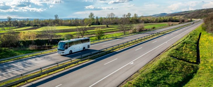 a charter bus driving along a long mountain road