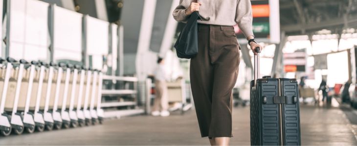 A businesswoman carrying a rolling suitcase