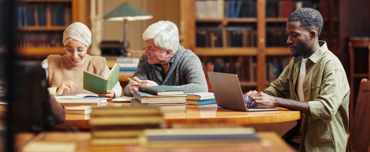a small diverse group of people looking at books in a library