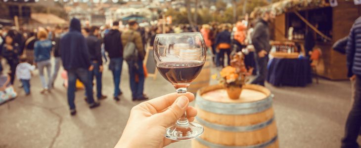 a person holding up a glass of wine at a busy wine festival